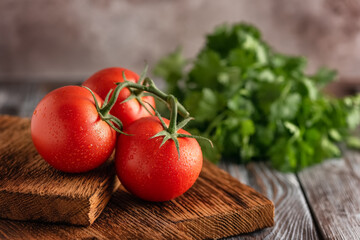 Fresh ripe tomatoes on a vintage cutting board, dark old wooden table. Selective focus. Side view.