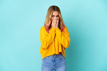 Young woman over isolated blue background happy and smiling covering mouth with hands