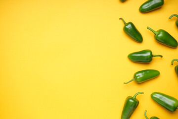 Green chili pepper. Group of jalapeno peppers on a yellow background, place for text, top view.