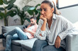 © nenetus - Angry young couple sitting on couch together and looking to opposite sides at home.