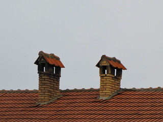 Poster - Roof of the house with tiles and two chimneys the house made of brick in the background of the sky