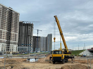 Wall Mural - Large yellow mobility modern industrial construction crane mounted on a truck is used in the construction of new housing, houses, buildings in a big city