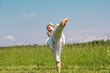 teenage girl training karate kata outdoors, performs the yoko geri kick with kiai