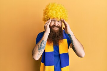 Sticker - Redhead man with long beard football hooligan cheering game wearing funny wig with hand on head for pain in head because stress. suffering migraine.