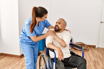 Senior man sitting on wheelchair and geriatric nurse at rehabilitation clinic