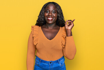 Poster - Young african woman wearing casual clothes with a big smile on face, pointing with hand and finger to the side looking at the camera.