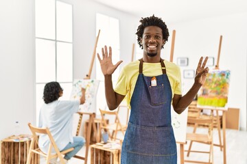 Sticker - African young man standing at art studio showing and pointing up with fingers number seven while smiling confident and happy.