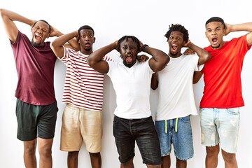 Poster - Young african group of friends standing together over isolated background crazy and scared with hands on head, afraid and surprised of shock with open mouth