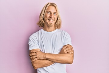 Canvas Print - Caucasian young man with long hair wearing casual white t shirt happy face smiling with crossed arms looking at the camera. positive person.