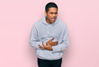 © Krakenimages.com - Young handsome hispanic man wearing casual sweatshirt with hand on stomach because nausea, painful disease feeling unwell. ache concept.
