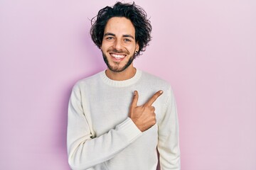 Poster - Handsome hispanic man wearing casual white sweater cheerful with a smile on face pointing with hand and finger up to the side with happy and natural expression