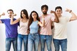 © Krakenimages.com - Group of young people standing together over isolated background strong person showing arm muscle, confident and proud of power