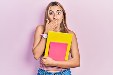 Canvas Print - Beautiful hispanic woman holding books covering mouth with hand, shocked and afraid for mistake. surprised expression