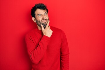 Poster - Handsome man with beard wearing casual red sweater thinking worried about a question, concerned and nervous with hand on chin