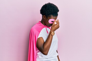 Canvas Print - Young african american girl wearing superhero mask and cape costume tired rubbing nose and eyes feeling fatigue and headache. stress and frustration concept.