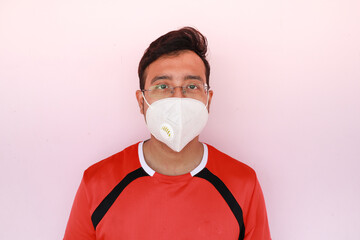 Canvas Print - Indian man wearing eyewear and a white facemask isolated on a pink background