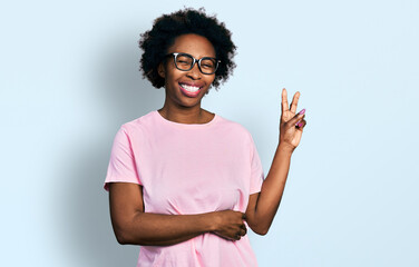 African american woman with afro hair wearing casual clothes and glasses smiling with happy face winking at the camera doing victory sign. number two.