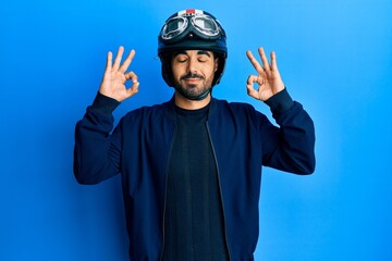 Canvas Print - Young hispanic man holding motorcycle helmet relax and smiling with eyes closed doing meditation gesture with fingers. yoga concept.