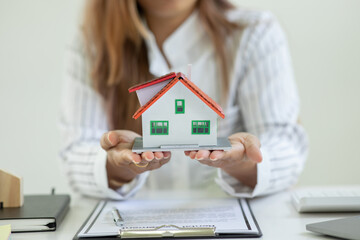 Close up of house model with business woman signs a purchase contract or mortgage for a home, Real estate concept.