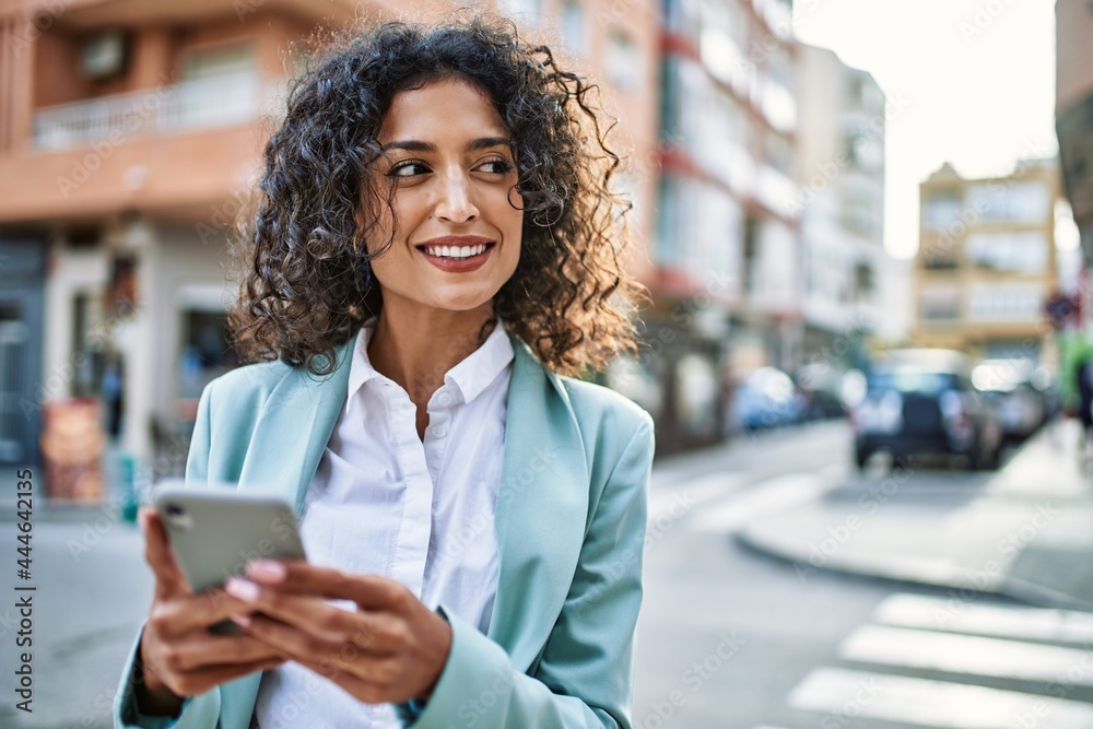 Young hispanic business woman wearing professional look smiling confident at the city using smartphone - obrazy, fototapety, plakaty 