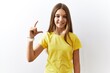 © Krakenimages.com - Young brunette teenager standing together over isolated background smiling and confident gesturing with hand doing small size sign with fingers looking and the camera. measure concept.