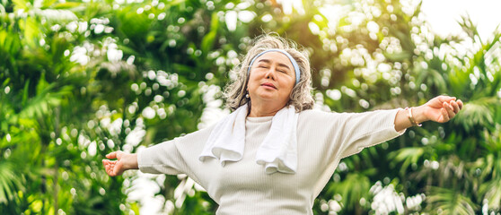 Portrait of happy senior old adult elderly asia women smiling standing and stretch her arms relax and enjoy with nature feeling breath fresh clean air in green park.Healthcare