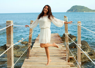 Young happy brunette woman on the bridge near sea, summer time.