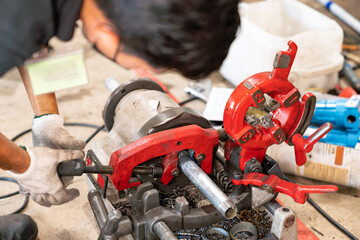 Close-up of pipe threading machine in use.