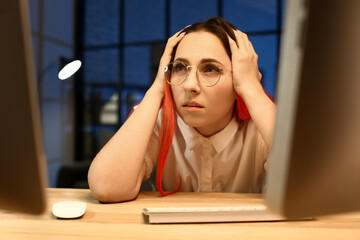 Wall Mural - Stressed female programmer working with computer in office at night