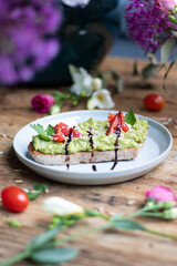 Wall Mural - Vertical shot of an avocado toast with tomatoes, sesame seeds, and balsamic sauce