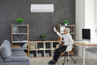 Senior businessman holding a remote control aimed at adjusting the air conditioner. Man makes a comfortable temperature in the office to improve working conditions on a hot day.