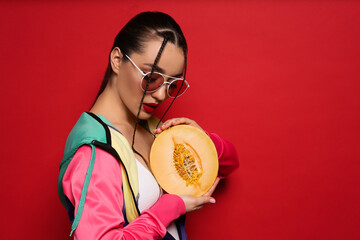 Wall Mural - Young woman with fresh melon on red background, space for text. Exotic fruit