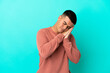 © luismolinero - Young handsome man over isolated blue background making sleep gesture in dorable expression