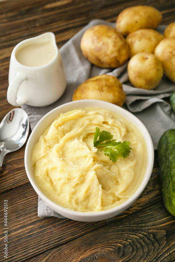 Bowl with tasty mashed potatoes and ingredients on wooden background