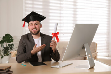 Wall Mural - Happy student with graduation hat and diploma at workplace in office