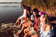 © Zoran Zeremski - Group of friends sitting on the edge of a pier having fun and enjoying a summer day at the lake.