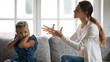 Stubborn small teen Caucasian girl child close cover ears ignore angry mom talking lecturing. Mad young mother scold quarrel with little daughter at home. Generation gap, domestic violence concept.