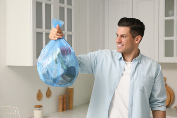 Wall Mural - Man holding full garbage bag at home