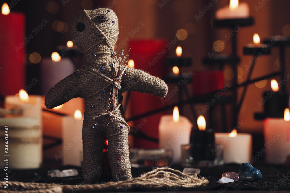 Voodoo doll with pins and dried flowers on table in room, space for text. Curse ceremony - obrazy, fototapety, plakaty 