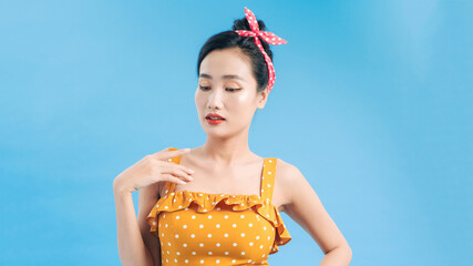 Wall Mural - Young beautiful woman posing in new casual yellow and white dotted dress on a blue background