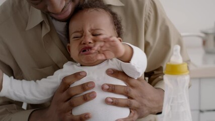 close up portrait of sad african american baby boy crying in fathers hands, feeling stressed and ann