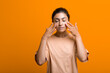 © primipil - Close up portrait of young indian american woman doing facebuilding yoga face gymnastics yoga self massage