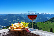 Fresch Tirol Cheese With Wine And Grapes Over Mountain Landscape