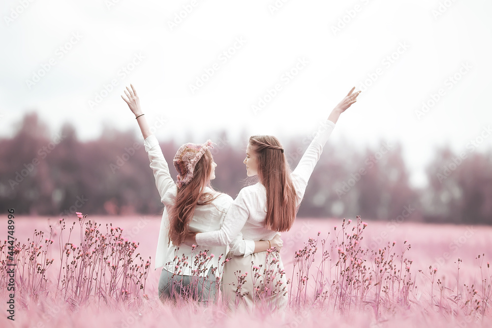 couple of girlfriends in a pink spring field beautiful freedom and friendship - obrazy, fototapety, plakaty 