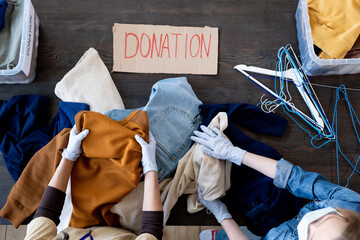 View of gloved females sorting donation clothes by table