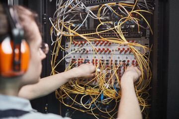 Wall Mural - Close up of young network engineer connecting cables in server room during maintenance work in data center, copy space