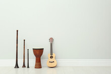 Ukulele, Vintage Bryolkas And Hand Drum Near White Wall Indoors, Space For Text. Musical Instruments