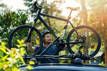 Man Takes Mountain Bike From The Car Roof Rack