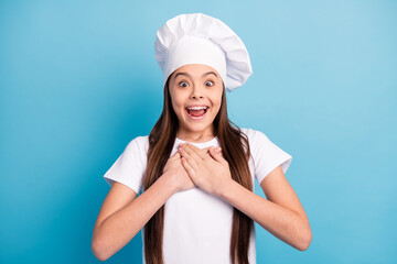 Poster - Photo of amazed astonished happy small lady hold hands chest gift wear hat chef isolated on blue color background