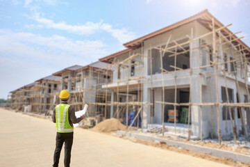 Wall Mural - young professional engineer in protective helmet and blueprints paper at the house building construction site